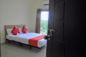 sypialnia z łóżkiem z czerwonymi poduszkami i oknem w obiekcie Hotel Relax Inn w mieście Nagpur