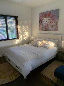 a bedroom with a large white bed with a painting on the wall at Moana Beach Sunset Holiday Accommodation B in Moana
