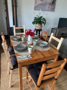 a wooden dining table with chairs and plates and flowers at Moana Beach Sunset Holiday Accommodation B in Moana