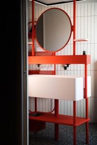 - une étagère rouge avec un miroir et un lavabo dans l'établissement YOU Are Deauville, à Deauville