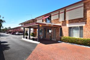 un edificio de ladrillo con un estacionamiento delante de él en Kennedy Drive Airport Motel, en Tweed Heads