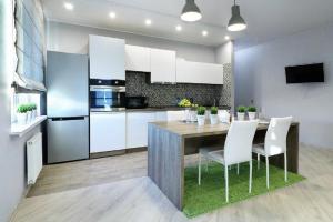 a kitchen with a dining table and white cabinets at PaulMarie Apartments on Yakubovskogo in Mogilev