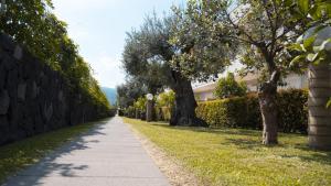 a sidewalk in a park with trees and a building at Villa Galati Resort in Mascali