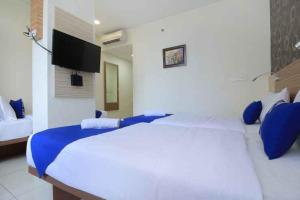 a bedroom with a large white bed with blue pillows at Smarthomm Ancol Jakarta in Jakarta