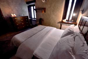 um quarto com uma cama branca, uma cómoda e janelas em Robur Marsorum Albergo Diffuso em Rocca di Mezzo