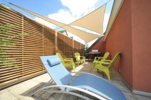 un patio con sillas verdes y una mesa en el balcón en Magic Moments Appartement, en Annecy