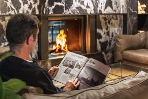 un hombre sentado en una silla leyendo una revista en Hotel Arbaso, en San Sebastián