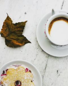 a plate of food and a cup of coffee and a leaf at Appartamento dei Sassetti in Savona