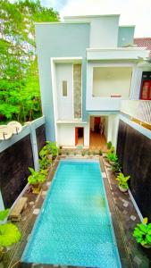a house with a swimming pool in front of a house at RedDoorz At Artomoro Guest House in Yogyakarta