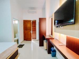 une chambre avec un lit et une télévision à écran plat dans l'établissement RedDoorz At Artomoro Guest House, à Yogyakarta