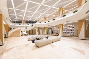 広州市にあるGHIC The Mulian Hotel of Bio-island Guangzhouの白い家具と階段が備わる広いロビー