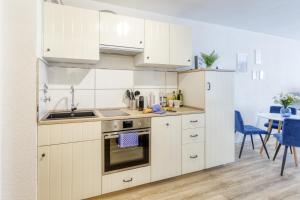 a kitchen with white cabinets and a sink and a table at Relax-Apartment mit Indoor-Pool, Fitness und Netflix am Bodensee in Uhldingen-Mühlhofen