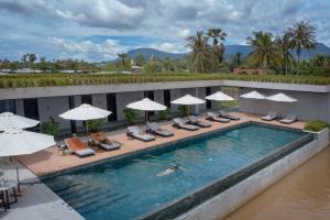 a pool with chairs and umbrellas on a hotel at Amber Kampot in Kampot