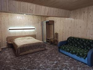 een slaapkamer met een bed en een bank erin bij У Павла in Yablunytsia