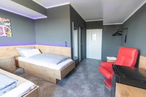 um quarto com uma cama e uma cadeira vermelha em Hotel Mecklenheide em Hanôver