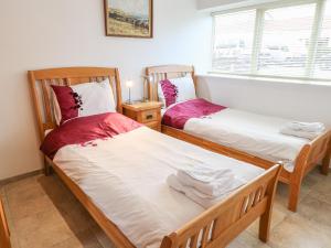 two twin beds in a room with a window at Mallard Cottage in Whitby