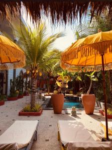 un complexe avec piscine, parasols et palmiers dans l'établissement Sunflower Stay And Surf, à Canggu