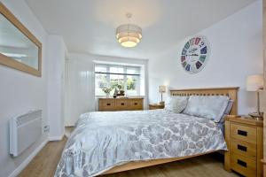 a bedroom with a bed and a clock on the wall at Anchor Cottage, Strete, Dartmouth in Strete