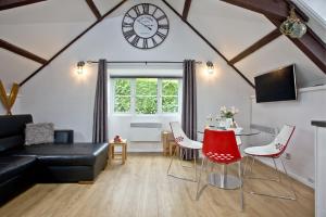 a living room with a table and a clock on the wall at Anchor Cottage, Strete, Dartmouth in Strete