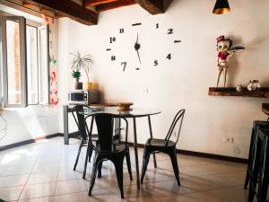 ein Esszimmer mit einem Tisch und einer Uhr an der Wand in der Unterkunft Grazioso bilocale pieno centro in Modena