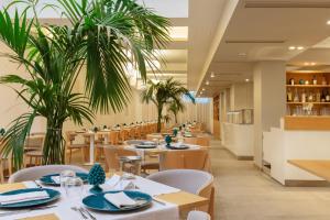 a restaurant with tables and chairs and palm trees at Albatros Beach Hotel in Letojanni