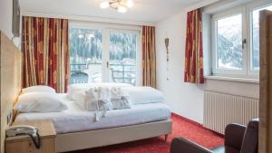 una camera da letto con un letto con cuscini bianchi e una finestra di Haus Battisti a Sankt Anton am Arlberg Altre 19 foto