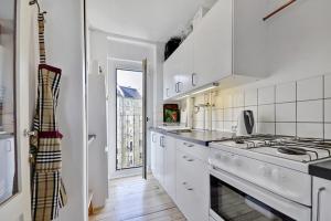 een witte keuken met een fornuis en een wastafel bij Stille og hyggelig lejlighed in Kopenhagen