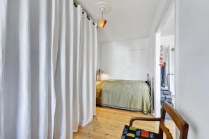 1 dormitorio con cama y cortina blanca en Stille og hyggelig lejlighed en Copenhague