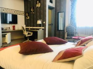 a bedroom with a bed with pillows and a desk at Hotel Le Griffon in Abidjan