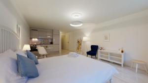 a bedroom with a large white bed and a kitchen at DA-DA Gallery Appart - modern and luxury studio in Boudry in Boudry