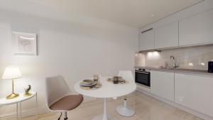 eine weiße Küche mit einem weißen Tisch und Stühlen in der Unterkunft DA-DA Gallery Appart - modern and luxury studio in Boudry in Boudry