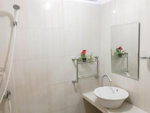 un bagno bianco con lavandino e specchio di Rumah Panggung Guest House Syariah Mitra RedDoorz a Cirebon
