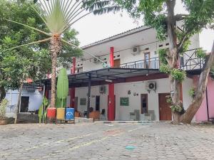 un bâtiment avec un palmier en face dans l'établissement Rumah Panggung Guest House Syariah Mitra RedDoorz, à Cirebon