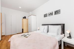 a white bedroom with a large bed with a pink blanket at Sunny Apartment Gdansk in Gdańsk