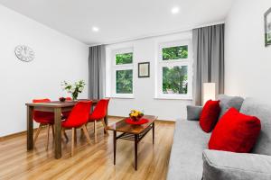 グダニスクにあるSunny Apartment Gdanskのリビングルーム(ソファ、赤い枕付きのテーブル付)