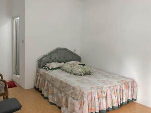 una camera da letto con un letto con una coperta e cuscini sopra di Rumah Panggung Guest House Syariah Mitra RedDoorz a Cirebon