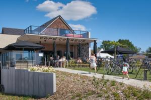 a group of people walking down a sidewalk in front of a cafe at Café Coureur Borgloon in Borgloon