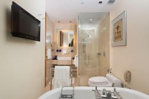 a bathroom with a tub and a toilet and a television at The Oberoi Bengaluru in Bangalore