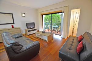 a living room with a leather couch and a television at EL SOL CORCOVADA APARTMENT - AC/POOL/WI-FI - ALBUFEIRA HOLIDAYS in Albufeira