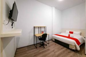 Dormitorio con cama, escritorio y TV en RedDoorz CBD Polonia Medan, en Medan