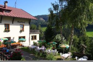 eine Gruppe von Personen, die außerhalb eines Gebäudes an Tischen sitzen in der Unterkunft Gasthof Luggau in Maria Luggau