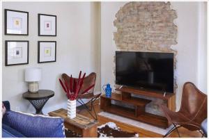 a living room with a flat screen tv and chairs at Heart of Highlands 3BR Loft in Louisville
