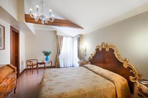 una camera con un grande letto e un lampadario a braccio di Residenza d'Epoca San Cassiano a Venezia