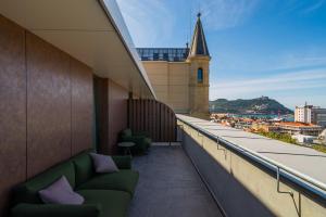 a balcony with green chairs and a clock tower at Catalonia Donosti in Donostia-San Sebastián