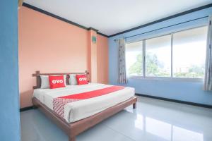 ein Schlafzimmer mit einem Bett mit roten Kissen darauf in der Unterkunft OYO 1145 Prickhom Garden Hotel in Nakhon Si Thammarat