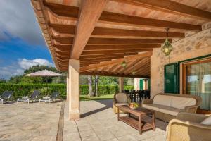 a patio with a couch and chairs under a wooden pergola at Villa Les Oliveres Antonia By SunVillas Mallorca in El Port