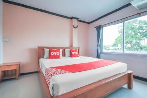 a bedroom with a bed with red pillows and a window at OYO 1145 Prickhom Garden Hotel in Nakhon Si Thammarat