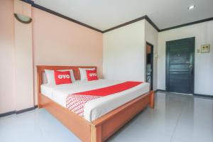a bedroom with a bed with red and white pillows at OYO 1145 Prickhom Garden Hotel in Nakhon Si Thammarat
