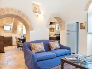 salon z niebieską kanapą i kuchnią w obiekcie Trulli Uliveto Acquafonda w Alberobello