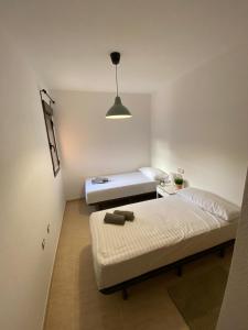 Dormitorio pequeño con 2 camas y lámpara en S&H La Malcriada, en San Juan de los Terreros